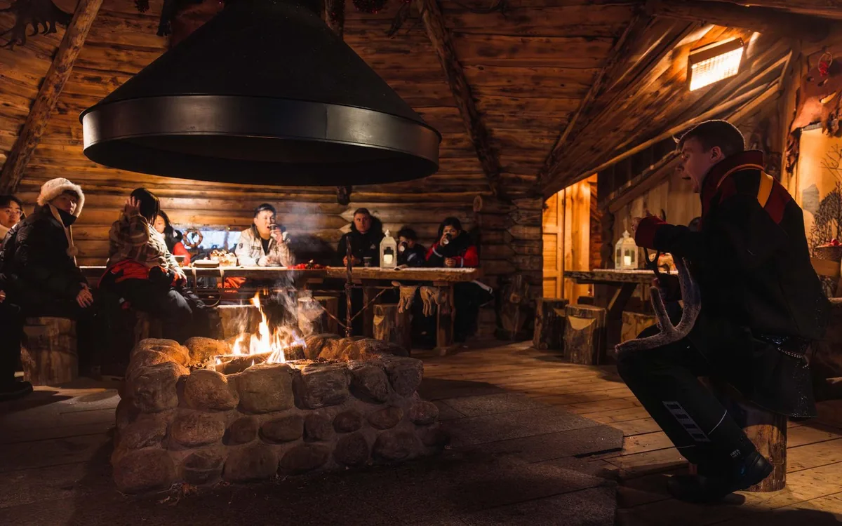 Eine hölzerne Kota mit offenem Feuer im Wald von Lappland